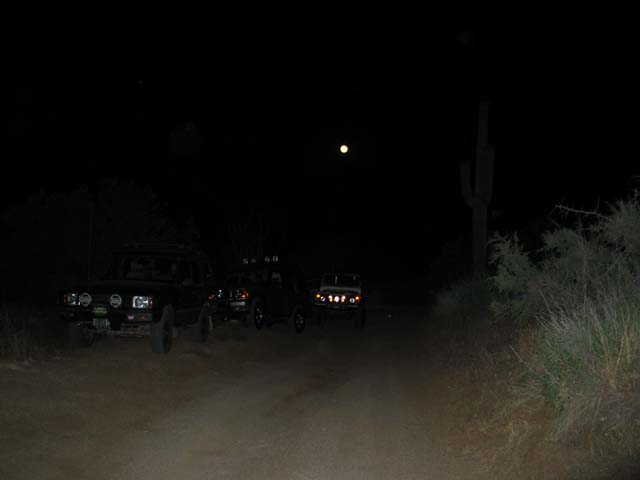 Trucks wait under a full moon at the beginning of the trail.