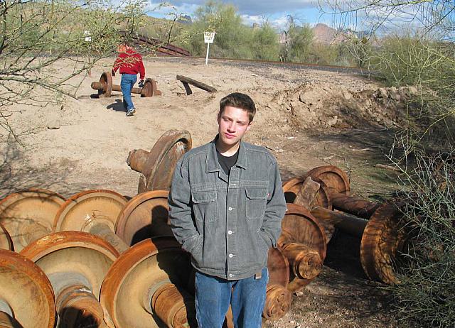 Austin standing by some old train wheels.